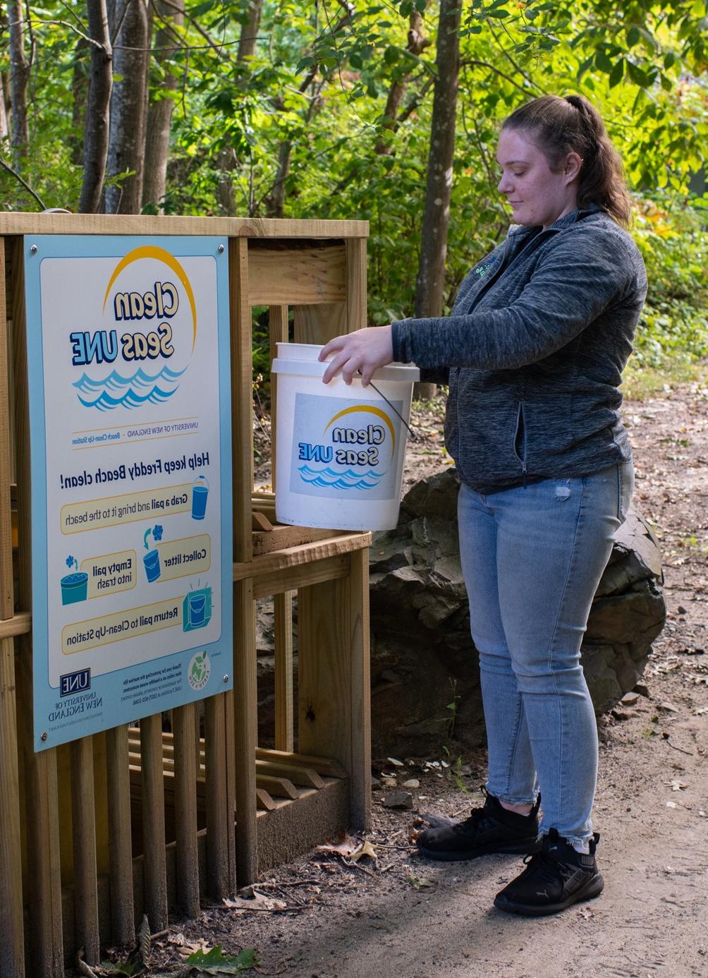 A student brings a bucket to the Clean the Seas drop-off location