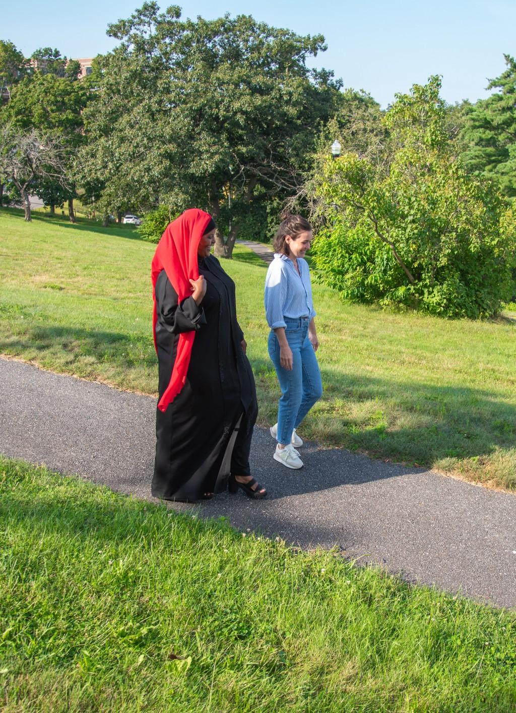 U N E药房.d. student Deqoo Mahamud walks with a university professional staff member
