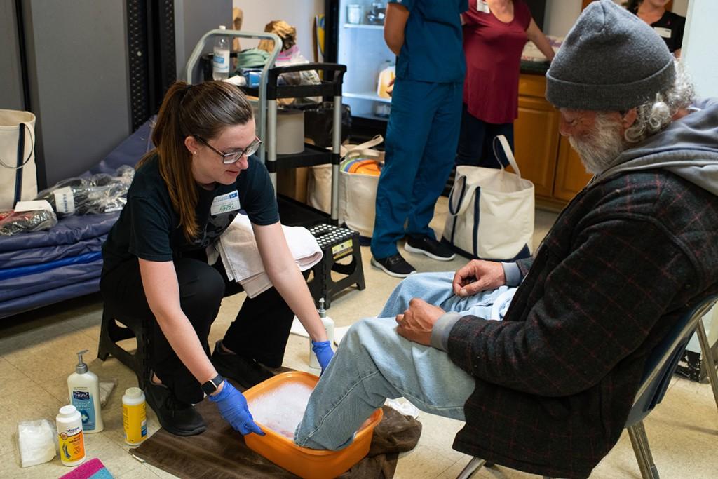 在缅因州波特兰的Milestone Recovery，一名学生正在给一名男子洗脚