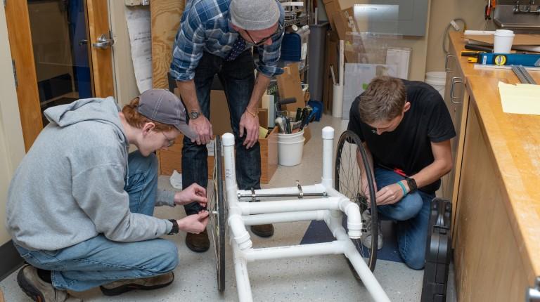 group of students and professor working on building wheelchair